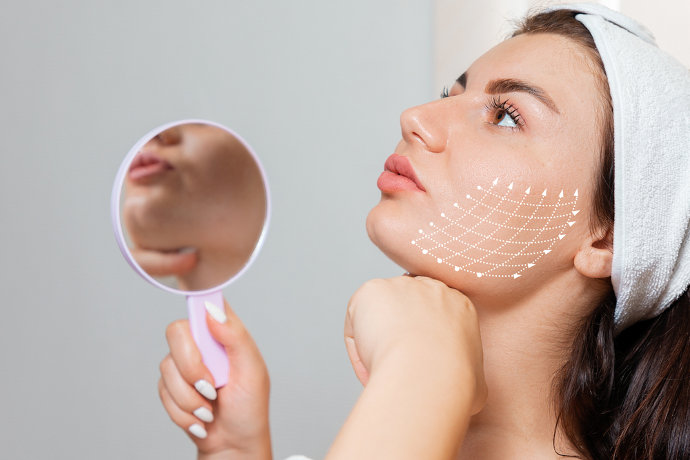 A woman examining her jawline in the mirror with markers for a PDO threads lift.