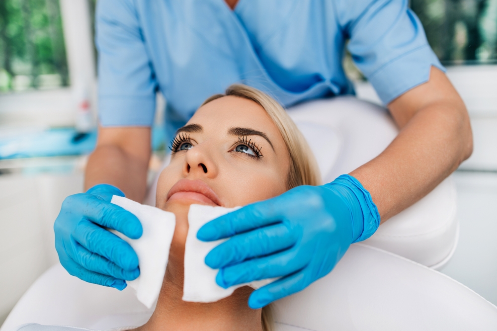 A microneedling session preparation with a professional cleaning the client's face before treatment.