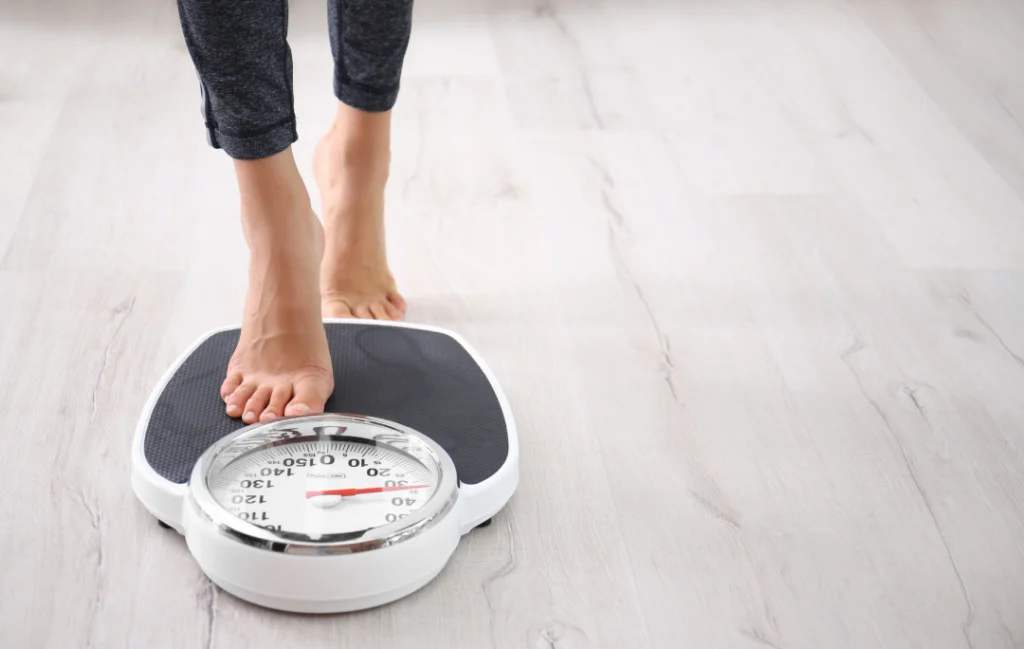 Person stepping on a scale during medical weight loss progress.