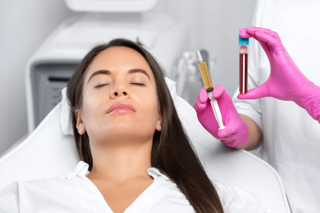 A medical professional holding a syringe of PRF and a vial of blood while preparing for a facial treatment session.