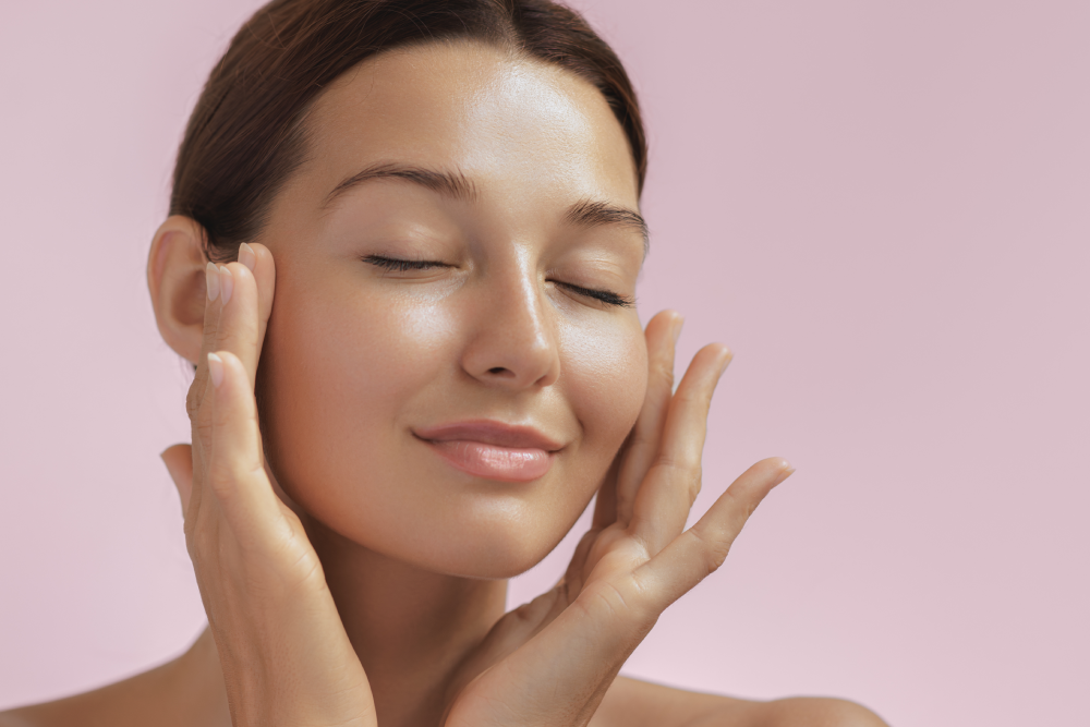 Woman with radiant skin touching her face after facials.
