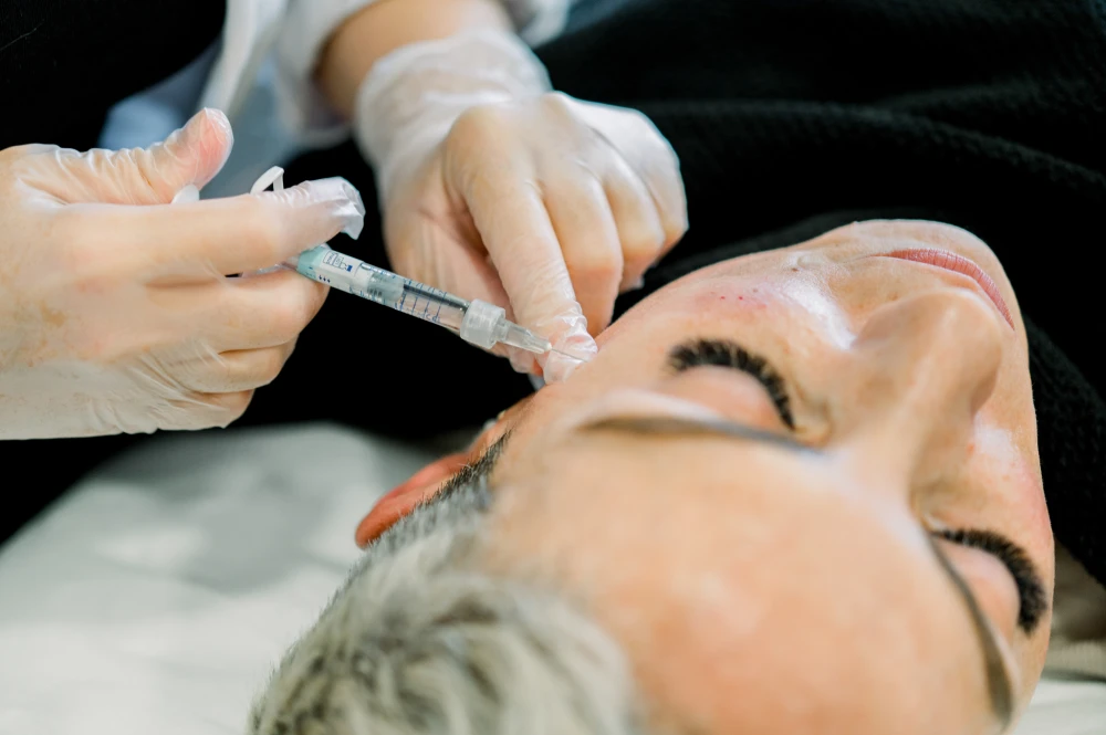A close-up of a patient receiving a dermal filler injection on the forehead.